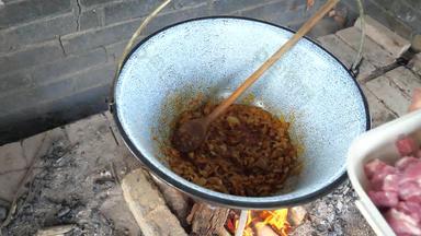 老板煎切碎洋葱深豆荚开放烧烤火准备传统的菜炖牛肉家庭朋友聚会，派对花园